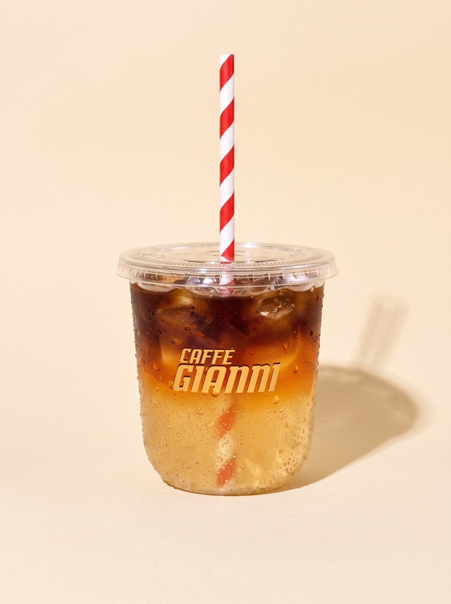 COFFEE - MATCHA SPRITZ with espresso: dark espresso over golden tonic and ice, striped straw, in a Caffè Gianni cup