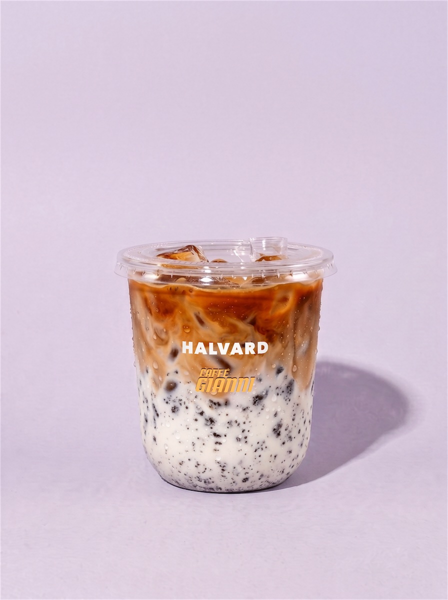 COOKIES AND CREAM, an iced latte with cookie crumbs through the milk, in a cup printed with the Halvard logo and a small Caffè Gianni logo